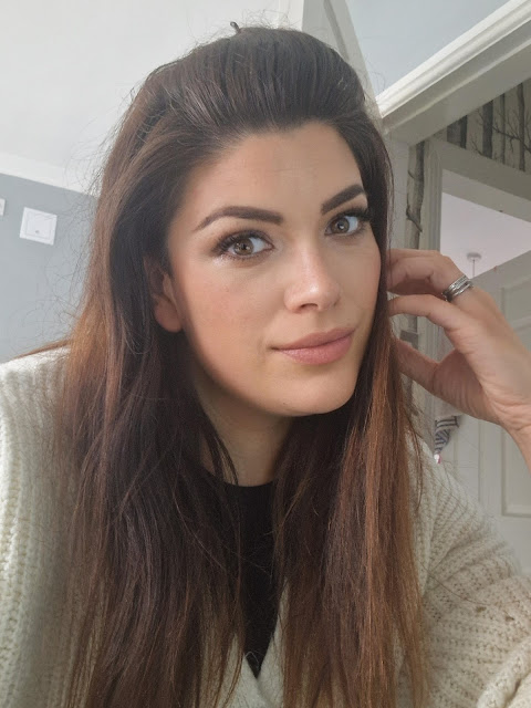 A brunette woman in her 30s showing a neatly made up face of makeup using Trinny London products